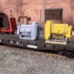 HO scale generator flat car load with cradle and chain tie downs in yard with unpainted version