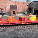 HO scale side view of a flatcar loaded with assorted colored cable drum spools in a rail yard setting