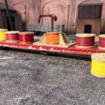Side view of a cable drum load featuring colorful spools on a flatcar in HO scale, displayed in a rail yard