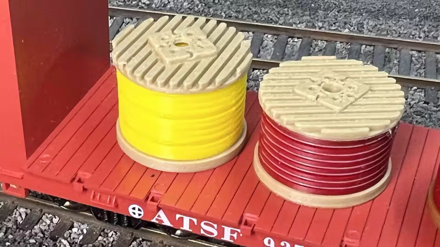 Top view of HO scale yellow and red cable drums on a model railroad layout.