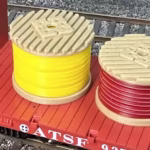 Top view of HO scale yellow and red cable drums on a model railroad layout.
